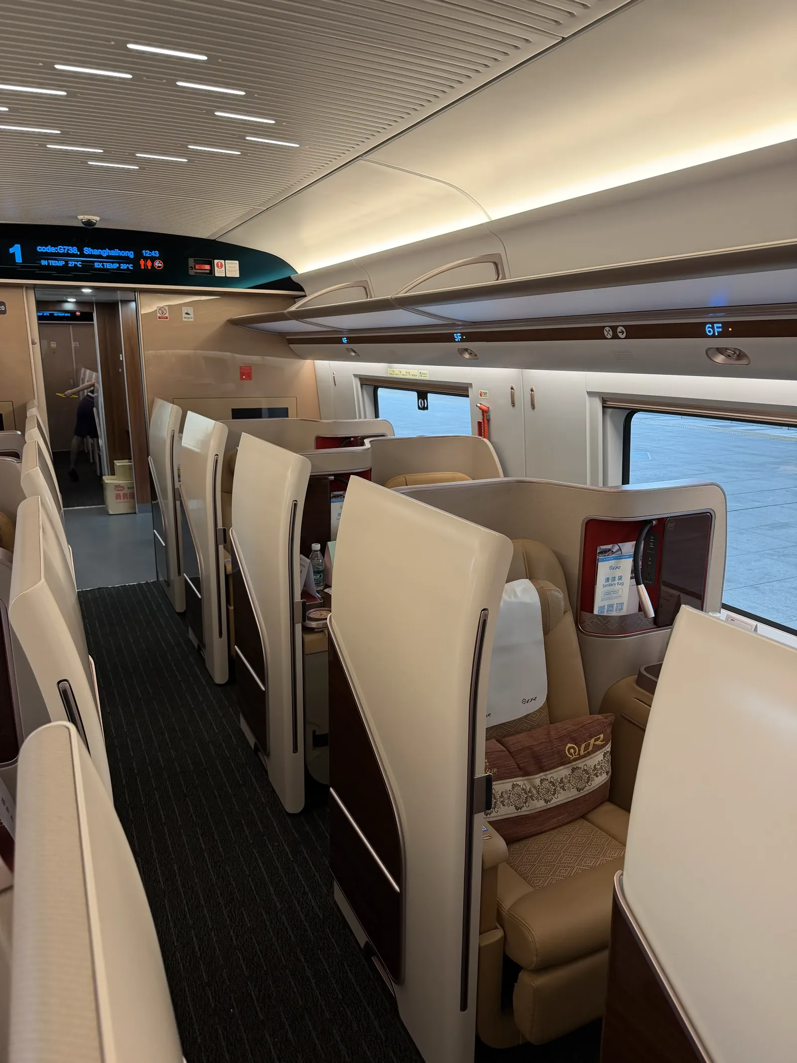 Blick durch den Business-Class-Wagen mit einzelnen, versetzt angeordneten Sitzen hinter hohen weißen Trennwänden, oben eine Anzeige mit der Zugnummer G738