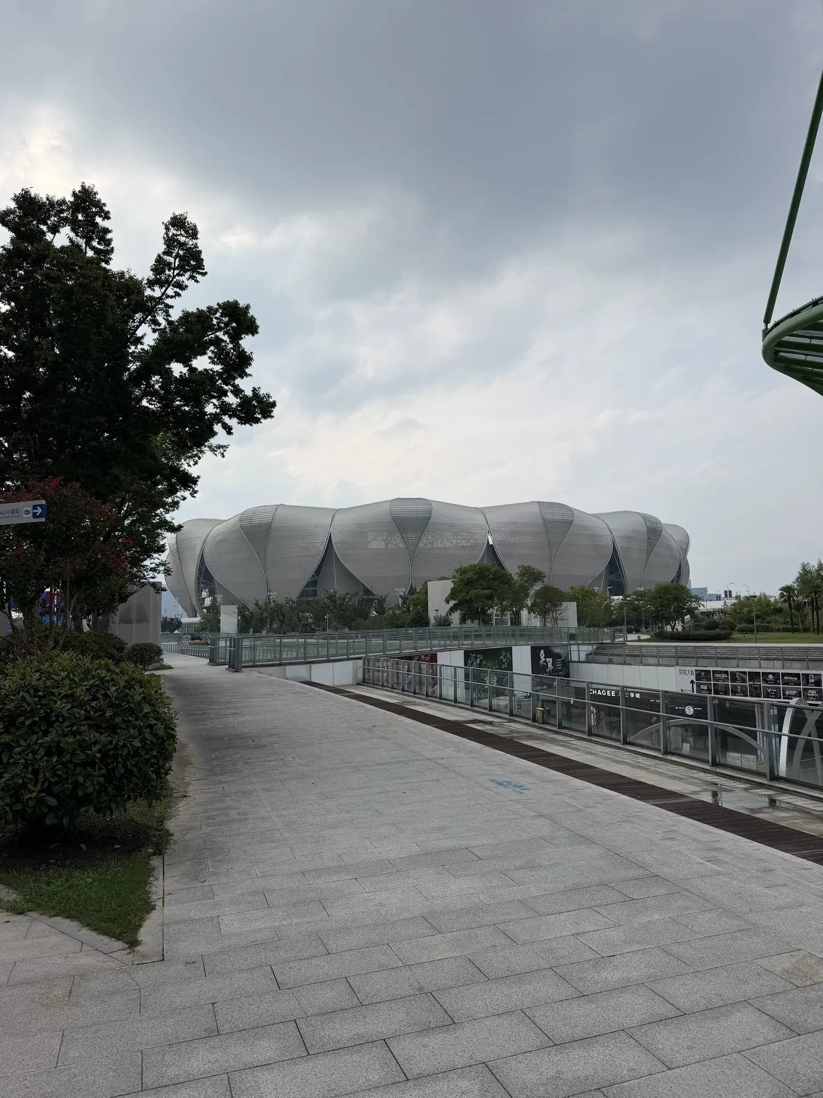 Das weiß-silberne Olympiastadion Big Lotus in Hangzhou mit blütenblattförmiger Dachkonstruktion, davor ein breiter Fußweg