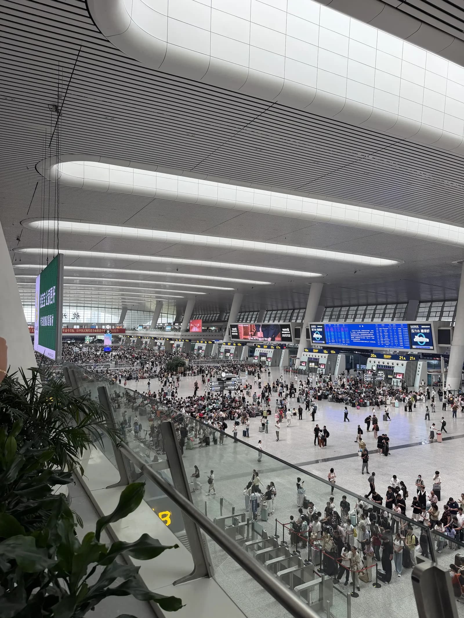 Große Bahnhofshalle in Hangzhou von oben mit Ticket-Gates, Anzeigetafeln und vielen Reisenden