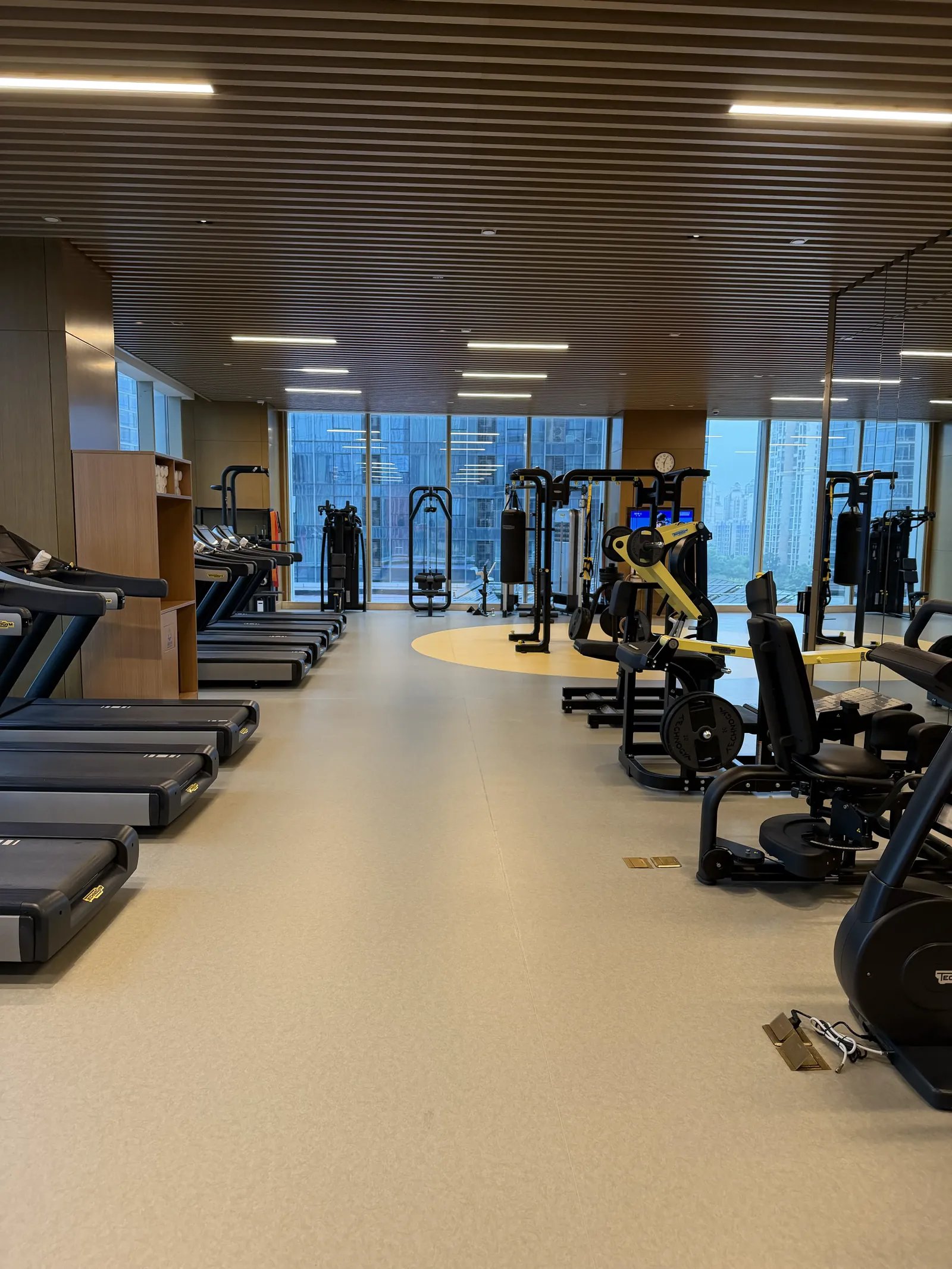 Großer Fitnessraum mit Laufbändern und Kraftgeräten vor einer Fensterfront